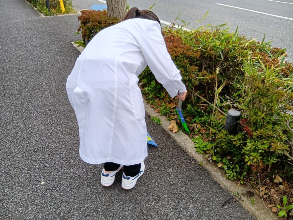 コスモス薬局東船橋店で薬学実習生が店舗前の清掃を行う様子