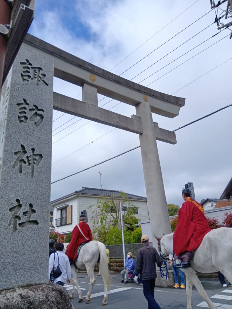 香取神宮神幸祭で諏訪神社の鳥居をくぐる馬上の行列の様子(香取市佐原)
