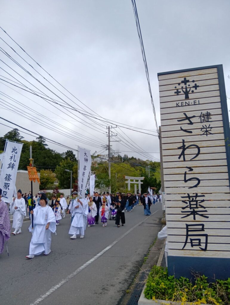 香取神宮神幸祭の行列が健栄さわら薬局の前を進む様子(香取市佐原)