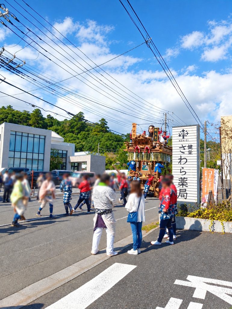 健栄さわら薬局の前を通る佐原の大祭の山車とお祭りの参加者