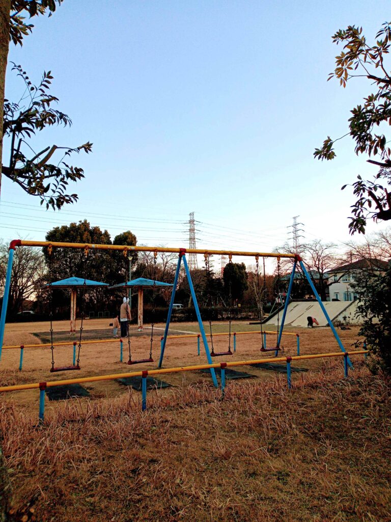 冬空の下、薬局裏手の北の下児童公園で遊ぶ親子
